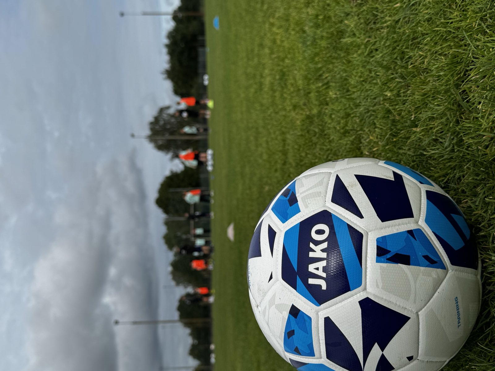 Trainingsball auf dem Rasen, im Hintergrund läuft die Einheit — Torwartschule Lausitz